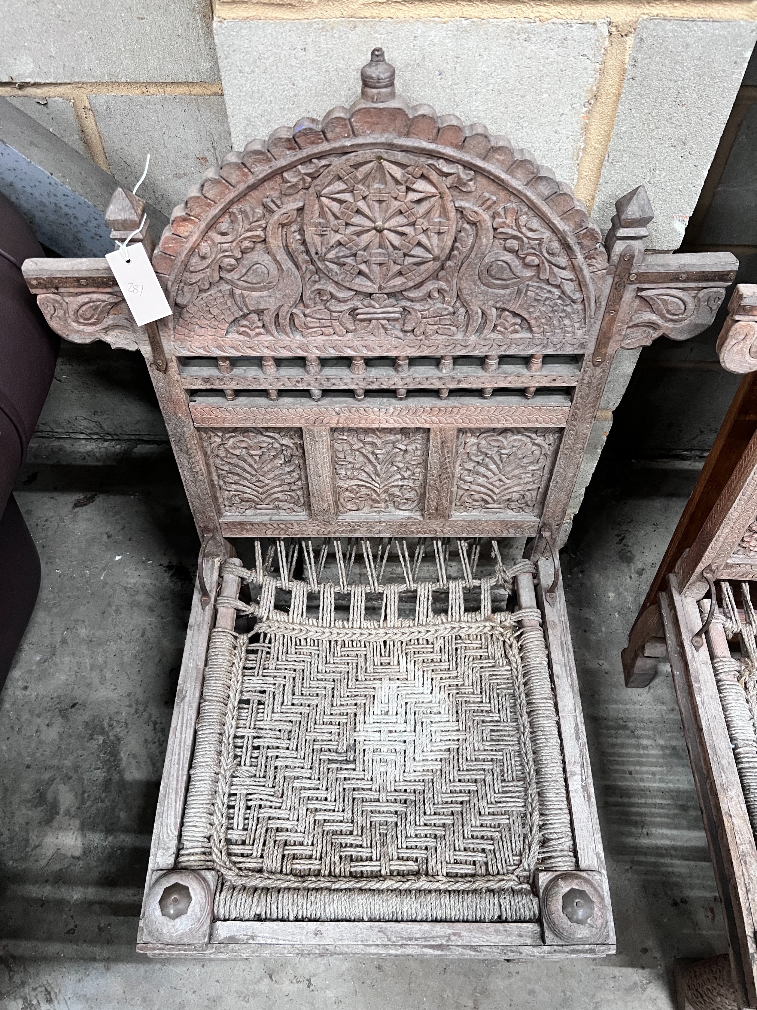 A pair of Indian carved teak low chairs with ropework seats, width 69cm *Please note the sale commences at 9am.